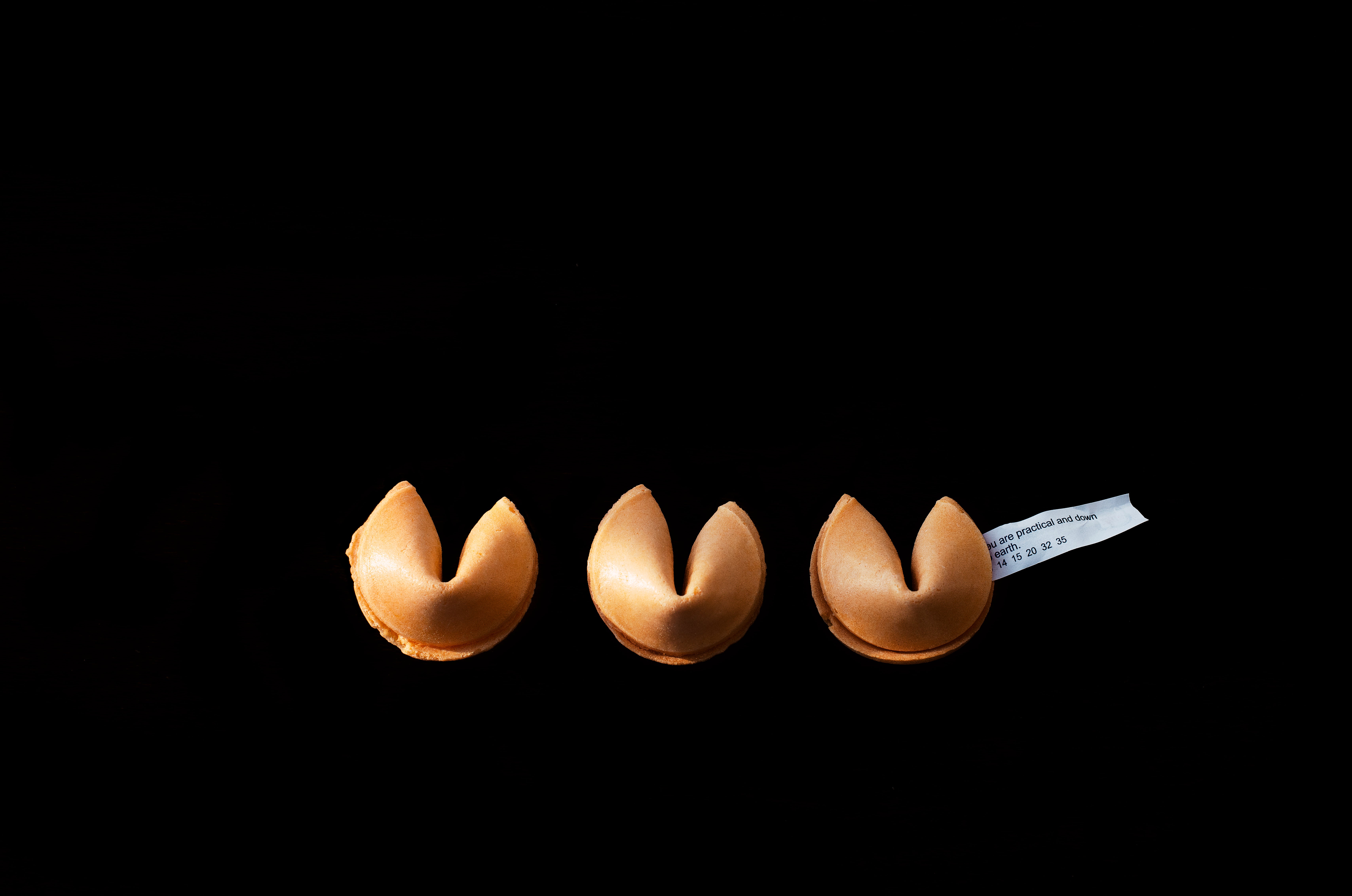 Browse free hd images of trio of fortune cookies sit unbroken on black background