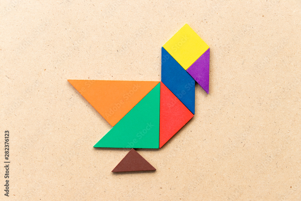 Color tangram puzzle in duck swan or goose shape on wood background photo