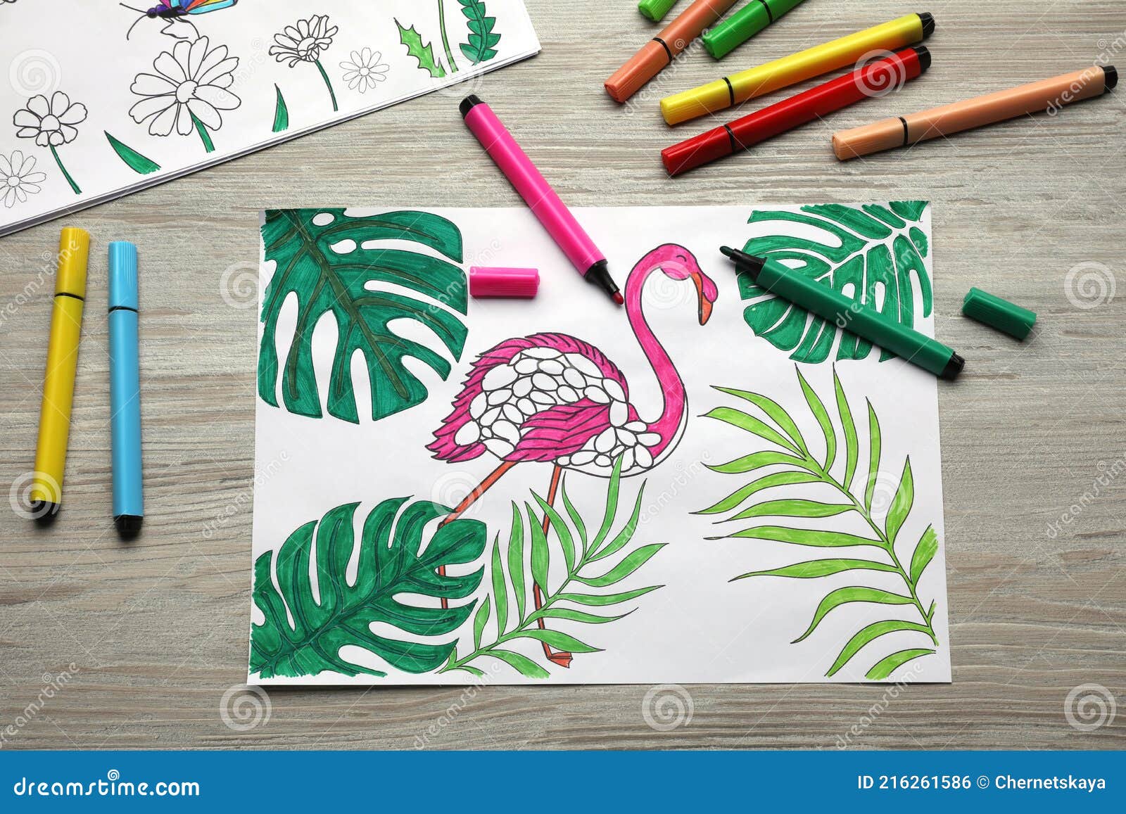 Coloring pages with children drawings and set of felt tip pens on wooden table flat lay stock photo