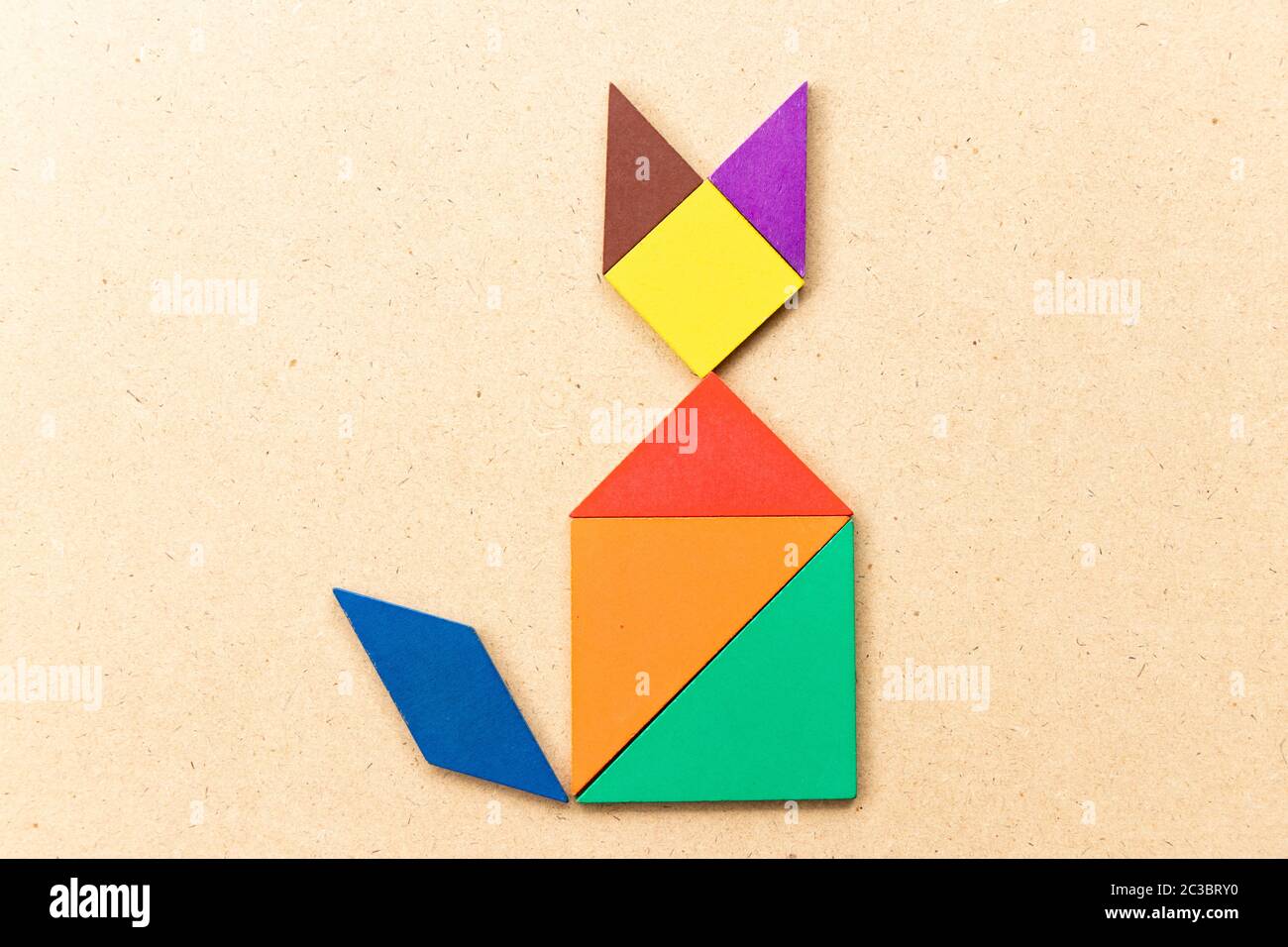 Color tangram puzzle in sitting cat shape on wood background stock photo
