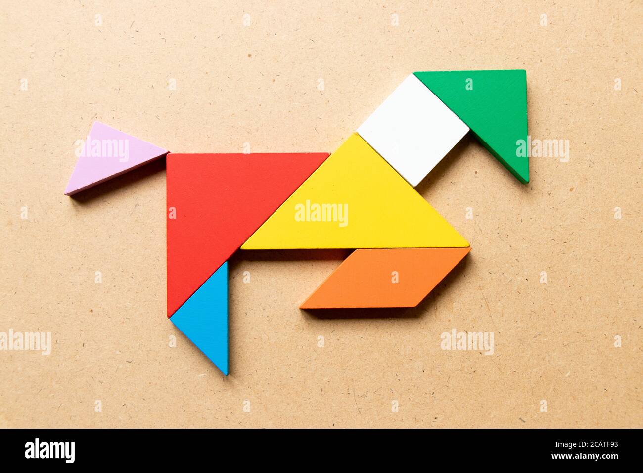 Color tangram puzzle in running horse shape on wood background stock photo
