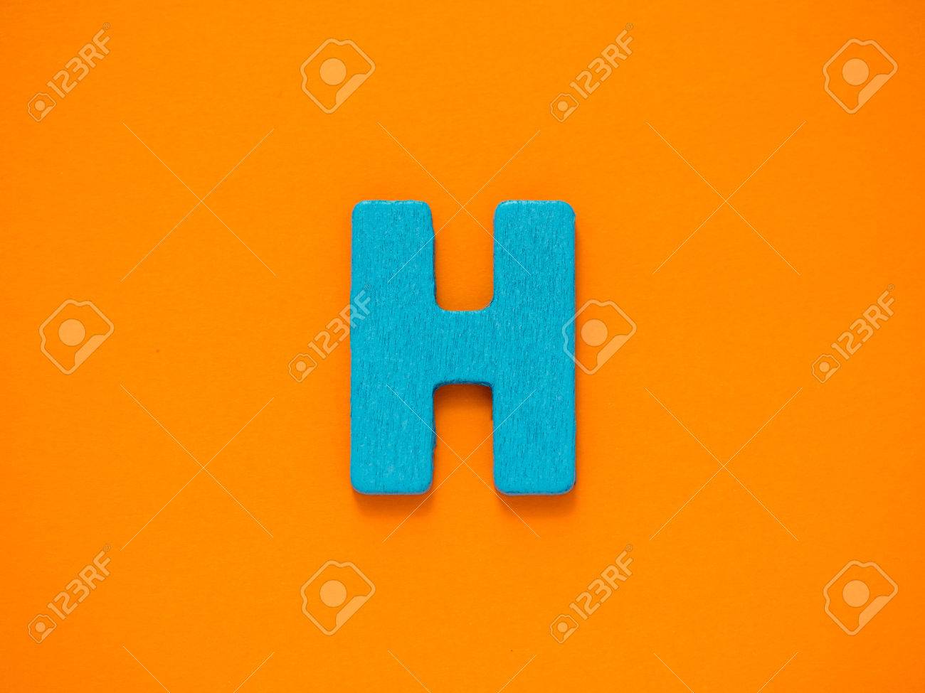 Capital letter h blue letter h from wood on orange background stock photo picture and royalty free image image